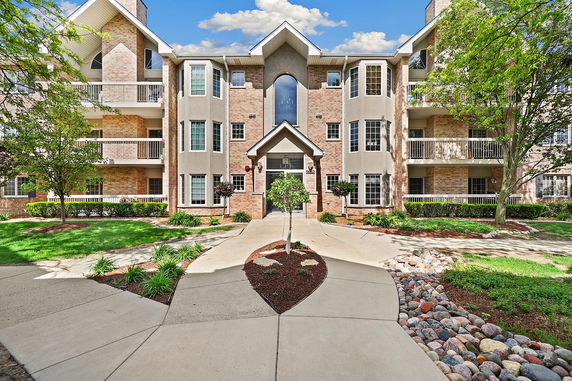 Front view of a three-story apartment building with balconies and landscaped surroundings.