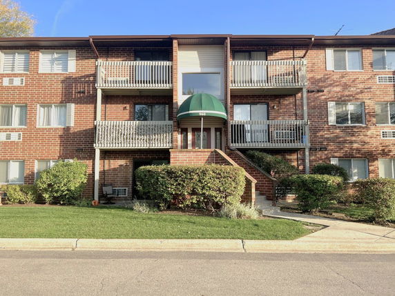 Front view of a three-story apartment building with balconies and brick exterior.