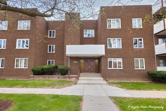 Front view of a brick apartment building with multiple windows and an entrance canopy.