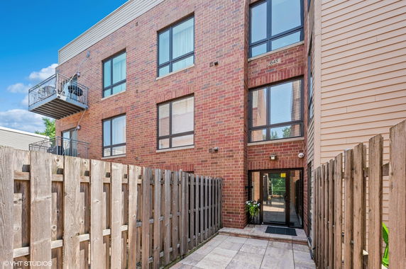 Front view of a brick residential building with balconies and a gated entrance.