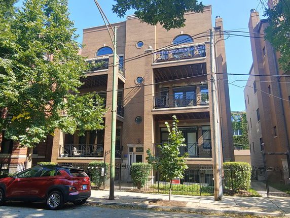 Front view of a multi-story brick apartment building with balconies.