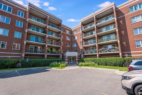 Front view of a multi-story brick apartment building with balconies.