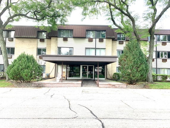 Front view of a multi-story apartment building with a covered entrance.