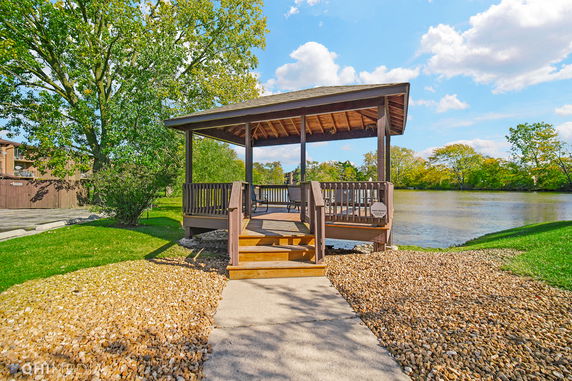 Gazebo overlooking a lake with trees and a pathway leading up to it.