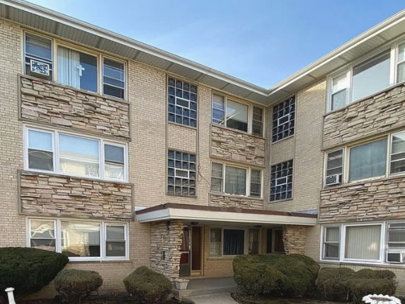 Front view of a multi-story apartment building with brick and stone exterior.