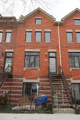 Front view of a multi-story brick townhouse with staircases leading to the entrance.
