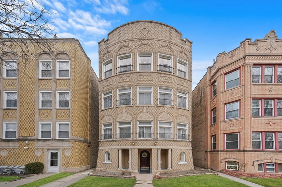 Front view of a multi-story brick apartment building with arched windows and balconies.