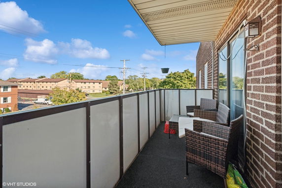 Balcony view with wicker chairs and table, overlooking residential area.