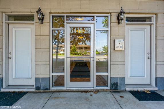 Front view of a building entrance with large glass doors and adjacent windows, flanked by two side doors.