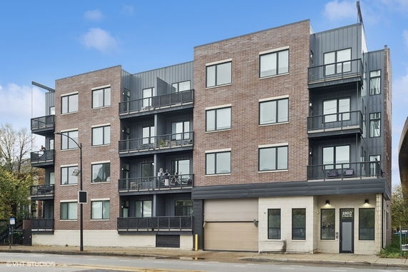 Front view of a multi-story apartment building with brick facade and balconies.