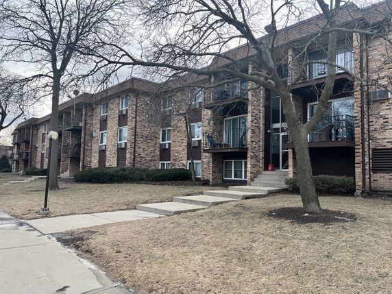 Front view of a multi-story brick apartment building with balconies.