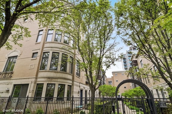 Front view of a multi-story residential building with large windows and surrounding trees.