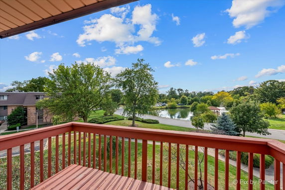 View of surrounding areas from a balcony overlooking a landscaped area and water body.