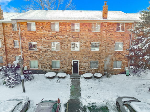 Front view of a three-story brick apartment building in winter.