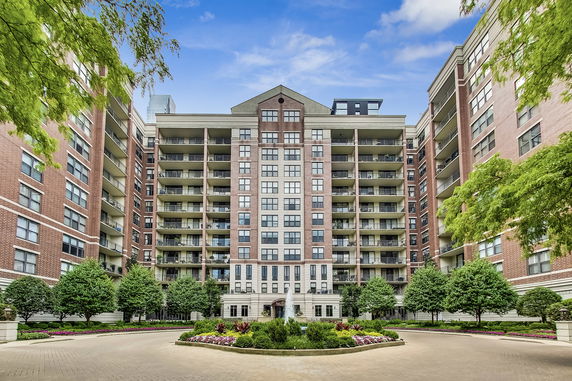 Front view of a multi-story residential building with balconies and a landscaped entrance.