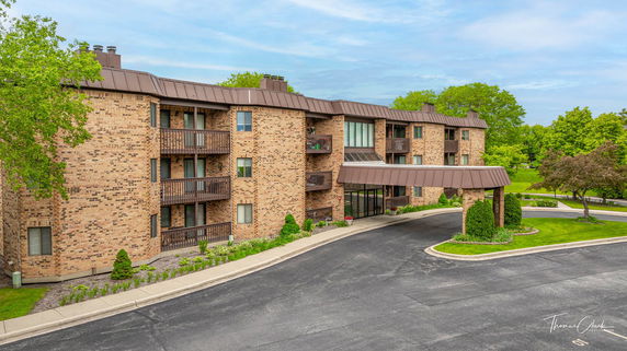 Front view of a multi-story brick apartment building with balconies.