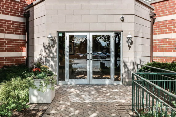 Entrance of a building with glass double doors and surrounding brick and stone facade.
