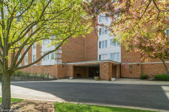 Front view of a multi-story brick building with large windows and a covered entrance.