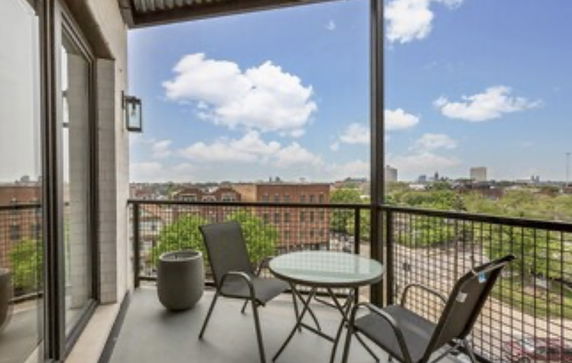 View from a balcony with a table and chairs overlooking a cityscape.