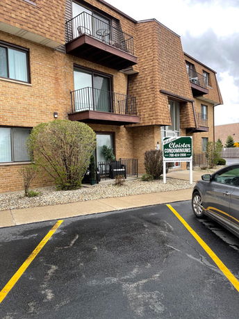 Front view of a brick condominium building with multiple balcony railings.