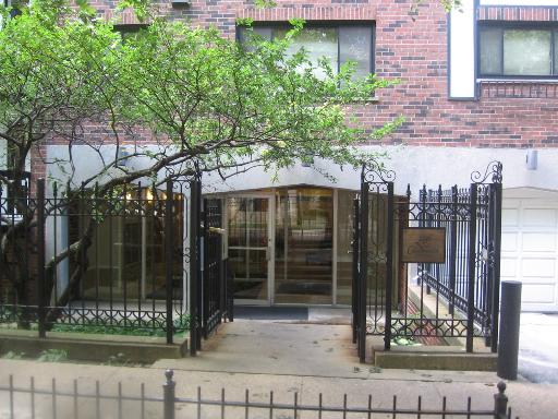 Front view of a building entrance with glass doors and iron fence.