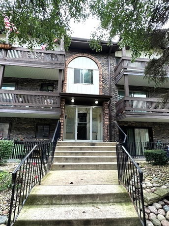 Front view of a multi-story building with balconies and a central entrance.