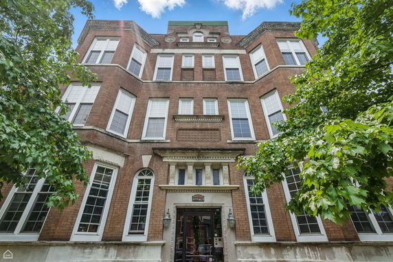 Front view of a multi-story brick building with large windows and decorative architectural details.
