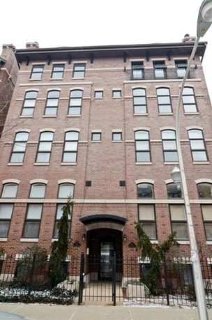 Front view of a multi-story brick building with a gated entrance.