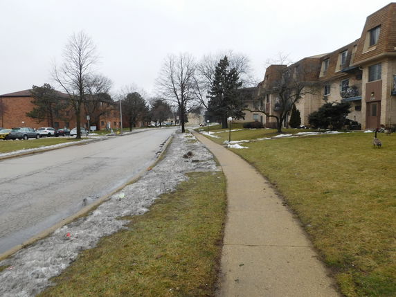 View of residential buildings alongside a road with some snow on the ground.