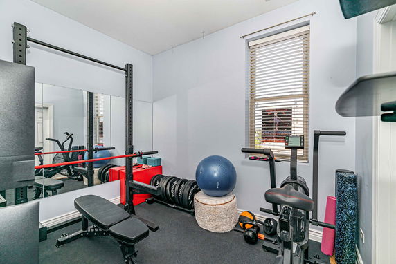 Indoor gym area with various exercise equipment including a bench press and exercise bike.