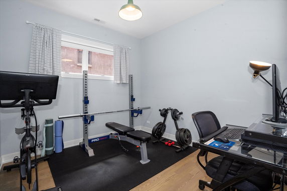 Home gym with exercise equipment and a computer desk.