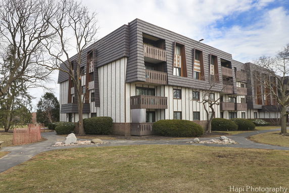Front view of a multi-story apartment building with balconies and modern design elements.
