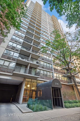 Front view of a high-rise apartment building with balconies and an entrance canopy.