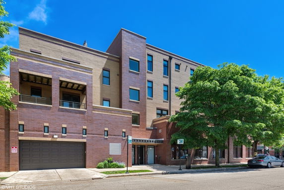 Front view of a multi-story brick building with large windows and a garage door.