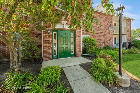 Front view of a brick building with a green door and path leading to the entrance.