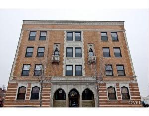 Front view of a multi-story brick building with decorative window details and arched doorways.
