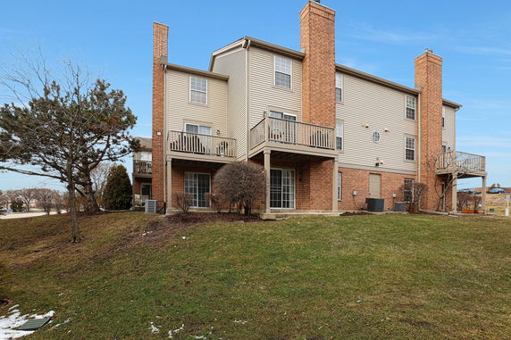 Rear view of a multi-story house with balconies and brick exterior.