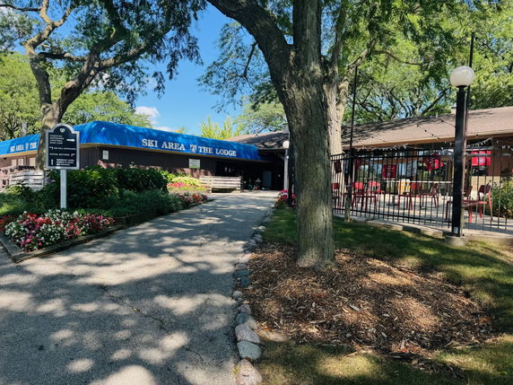 Front view of a lodge building with a blue awning labeled 'Ski Area the Lodge.'