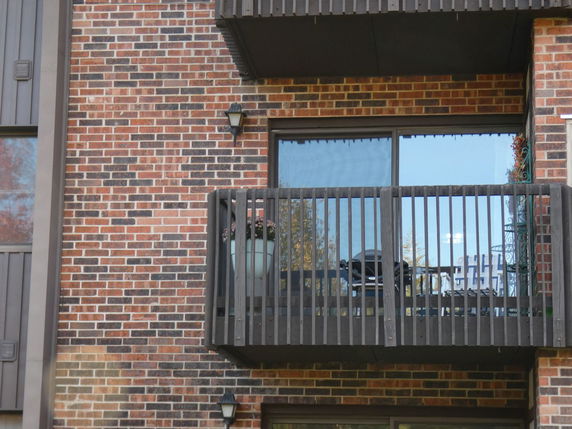 Front view of a building with a balcony and brick exterior.