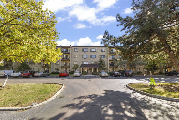 Front view of a multi-story apartment building with parking area in front.