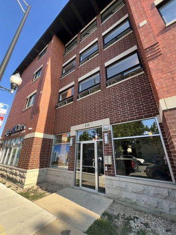 Front view of a multi-story brick building with large windows and a glass entrance.