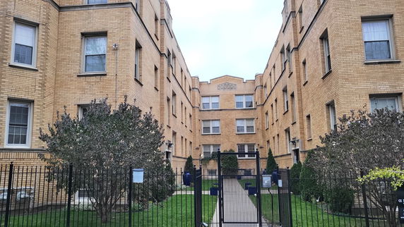 Front view of an apartment building with a gated entrance.