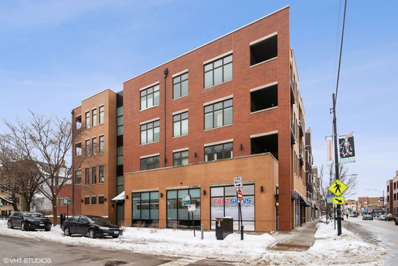 Front view of a multi-story brick building on a snowy street corner.