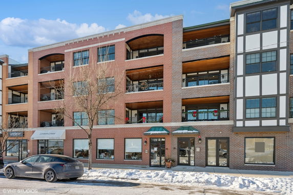 Front view of a multi-story brick building with balconies and large windows.