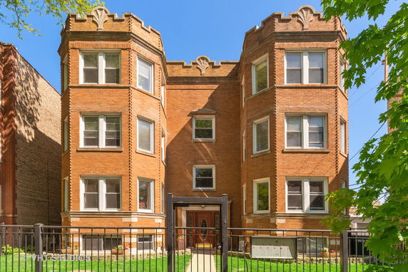Front view of a brick multi-story building with decorative architectural details.