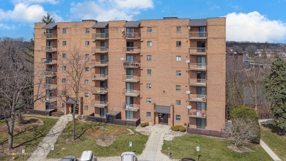 Front view of a multi-story brick apartment building with balconies.
