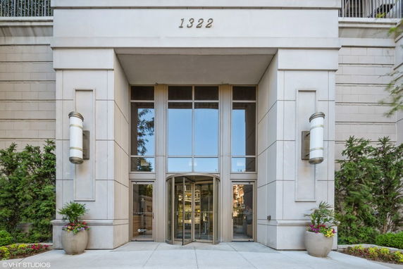 Front view of a building entrance with revolving doors and large windows.