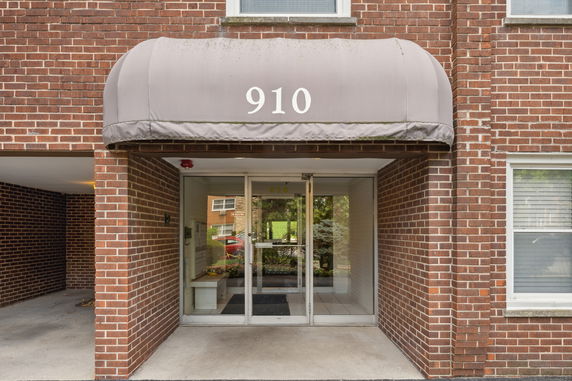 Entrance of a brick building with a glass door and canopy labeled 910.