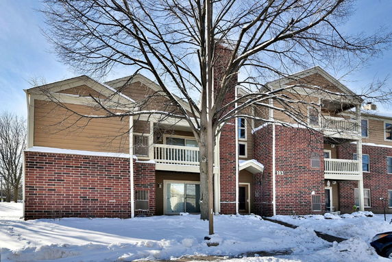 Front view of a multi-story building with brick and siding exterior and balconies.