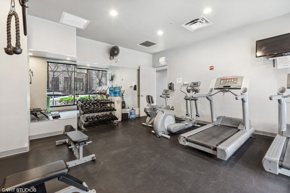 Indoor gym area with exercise equipment including treadmills and weights.